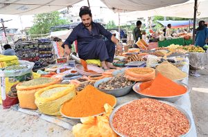 A woman browses colorful stoles at a stall in Sunday Bazaar