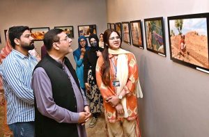 A student keenly observe a photo in photo and painting exhibition organized by the Department of Arts and Design at Zubaida Agha Art Gallery in connection with Labour Day.