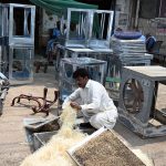 Worker busy in filling husk in frames of room air coolers at his workplace