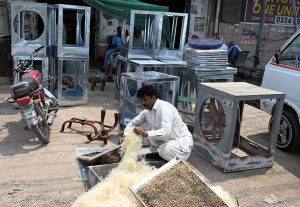 Worker busy in filling husk in frames of room air coolers at his workplace