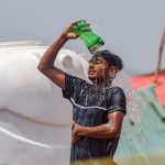A boy throws water on his body to protect himself from the intense heat at the Bhatta Chowk livestock market