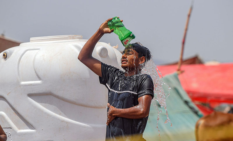 A boy throws water on his body to protect himself from the intense heat at the Bhatta Chowk livestock market