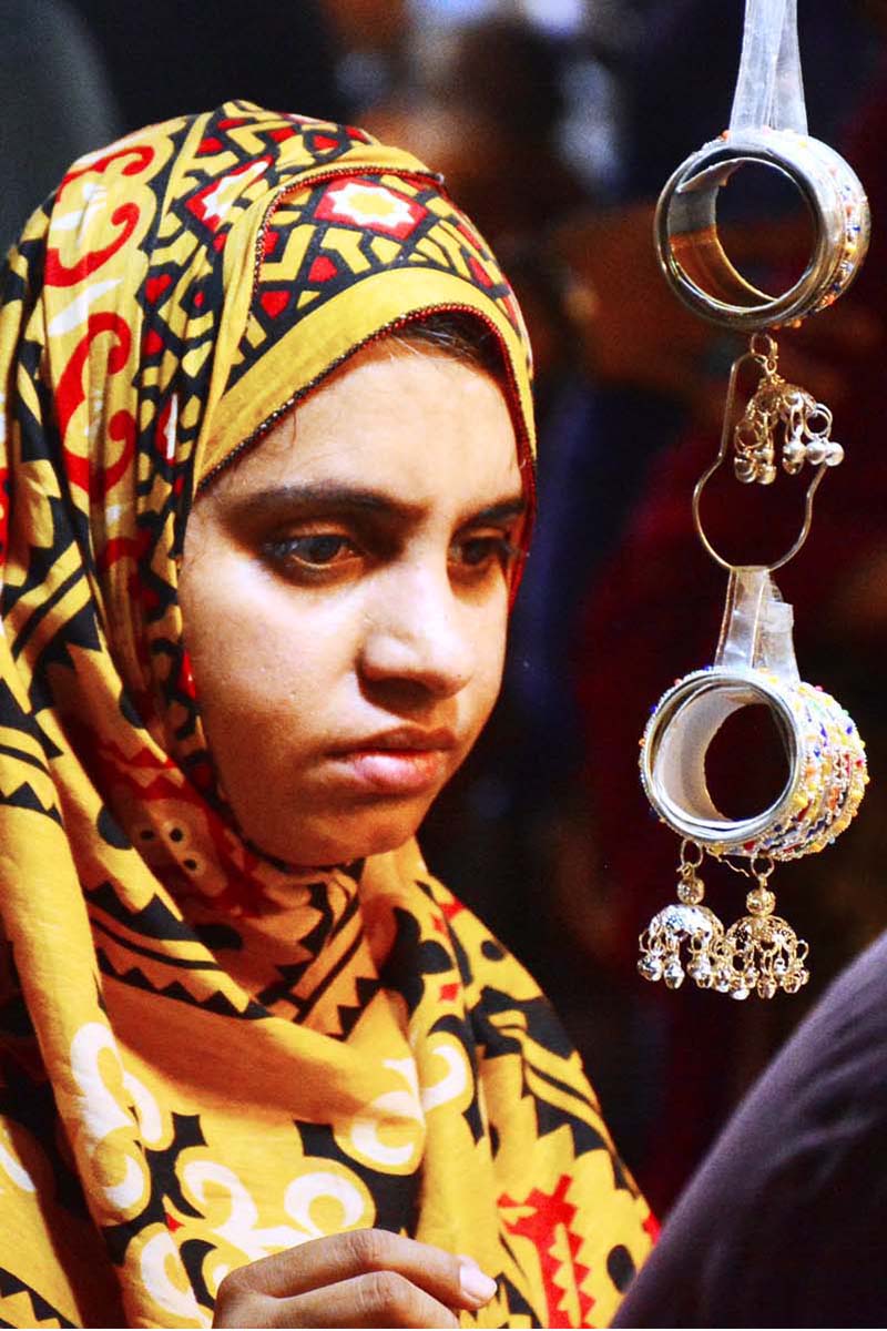 Women are busy selecting and purchasing artificial jewelry from vendor stall in preparation of Eid-ul-Azha at Resham Bazaar