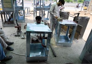 Worker busy in filling husk in frames of room air coolers at his workplace