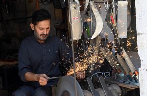A blacksmith sharpens knives to be used for slaughtering sacrificial animals ahead of the upcoming Eid al-Adha at Chowk Noonarian Khuda Bakhsh Road