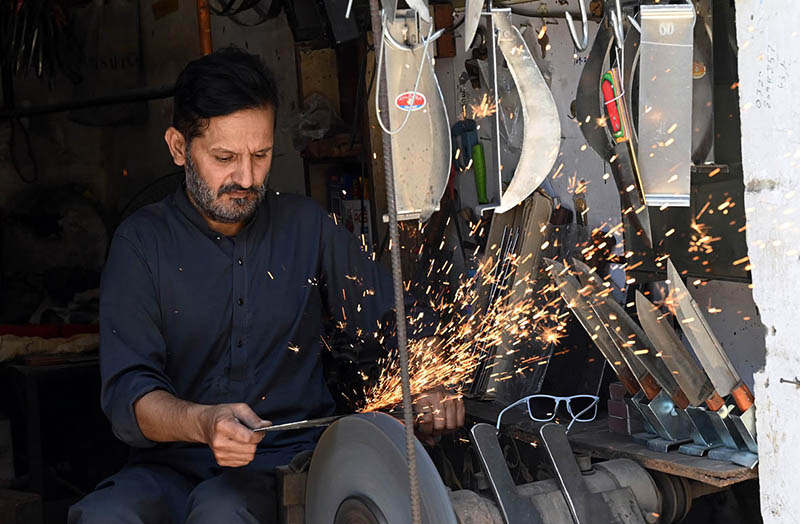A blacksmith sharpens knives to be used for slaughtering sacrificial animals ahead of the upcoming Eid al-Adha at Chowk Noonarian Khuda Bakhsh Road
