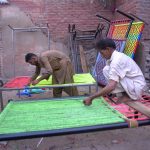 Workers prepare traditional charpoys (woven beds) at their workshop
