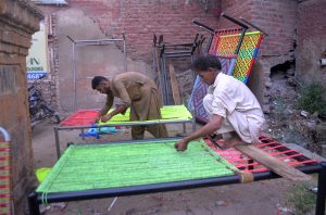 Workers prepare traditional charpoys (woven beds) at their workshop