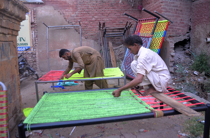 Workers prepare traditional charpoys (woven beds) at their workshop