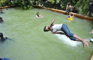 Youngsters enjoy bathing under a running tube-well to get relief from the scorching heat at Khesana Mori village.