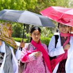 Medical students walk under an umbrella to protect themselves from intense heat and direct sunlight during hot weather at LUMHS Jamshoro