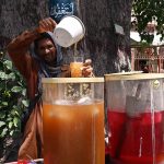 A vendor prepare and sells sweet drinks on the roadside during hot weather in the city