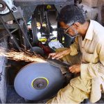 A blacksmith is busy sharpening knives and axes to be used for slaughtering sacrificial animals during Eidul Azha