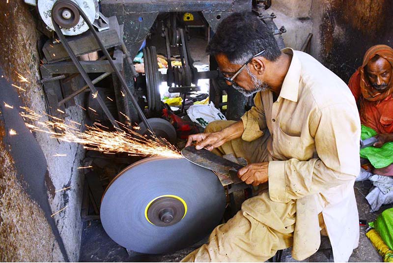 A blacksmith is busy sharpening knives and axes to be used for slaughtering sacrificial animals during Eidul Azha