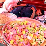 A vendor takes an afternoon nap during a hot day near the Railway Station in the city