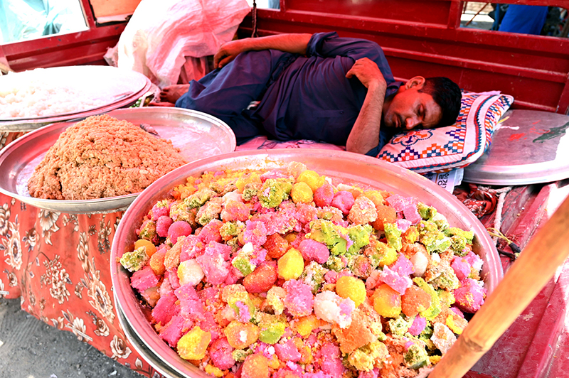 A vendor takes an afternoon nap during a hot day near the Railway Station in the city