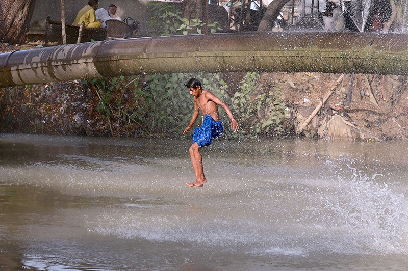 A youngster dives into a canal at Hala Naka to escape the summer heat
