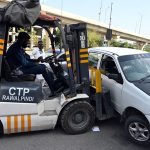 Traffic police personnel remove an illegally parked car with the help of a car lifter along Murree Road in the Commercial Market area