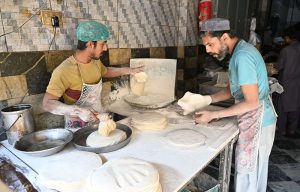 A worker prepares samosa patti on a huge tawa, rolling the dough by hand step by step at his workplace