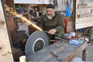 A blacksmith is busy sharpening knives and axes to be used for slaughtering sacrificial animals during Eidul Azha.