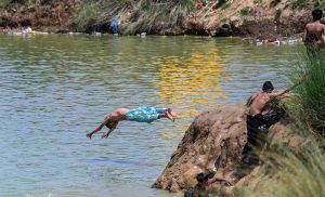 A youngster jumps into a rainwater pond to cool off during hot weather in I-12.