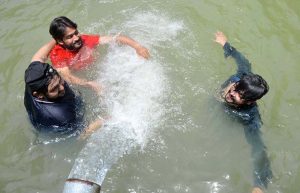 Youngsters enjoy bathing under a running tube-well to get relief from the scorching heat at Khesana Mori village.