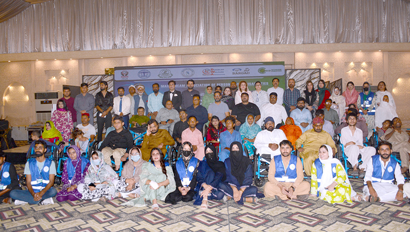 Divisional Director Social Welfare Umme Farwa Hamdani poses for a group photo with differently-abled persons during a wheelchair distribution ceremony organized by the Mainstream Association of Disabled Persons