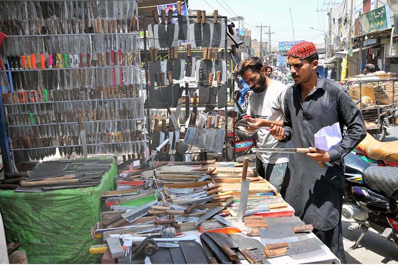 People are busy purchasing knives from a roadside setup to be used for slaughtering sacrificial animals during Eidul Azha