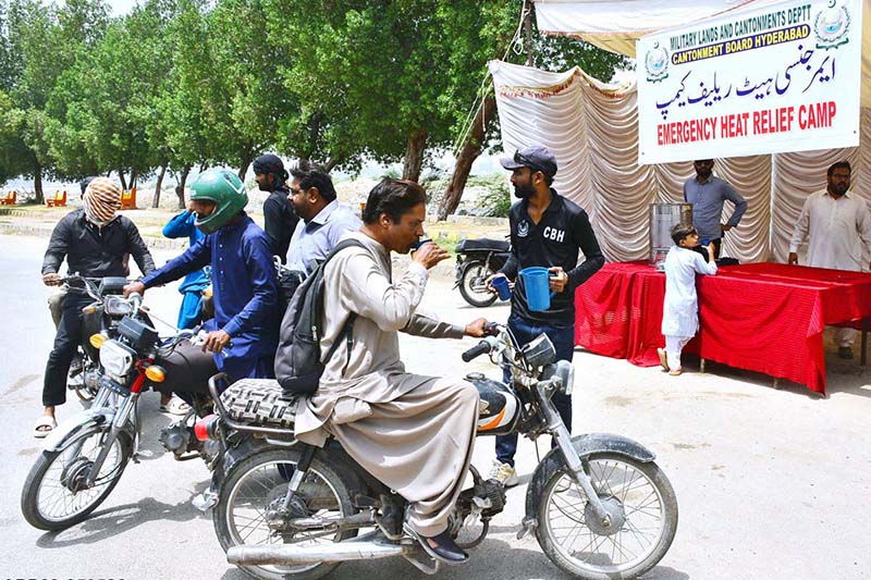 Workers of the Cantonment Board Hyderabad serve chilled drinking water to citizens at a heatstroke relief camp set up on Alamgir Road amid scorching weather conditions