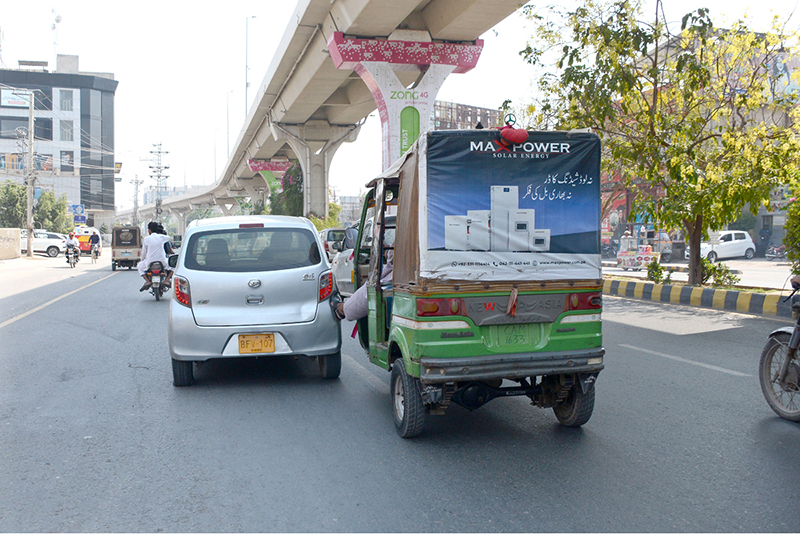 An auto-rickshaw driver uses his foot to propel his vehicle forward after running low on fuel while travelling along Bosan Road