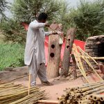 A worker straightens raw bamboo poles at his workplace