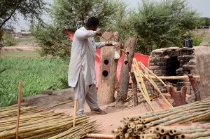 A worker straightens raw bamboo poles at his workplace