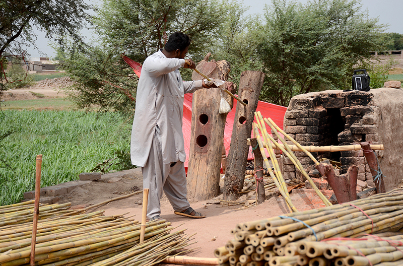 A worker straightens raw bamboo poles at his workplace