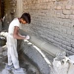A labourer applies decorative designs to a cement pillar at his roadside workplace area