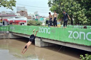 Youngster jumping and bathing in a Canal to get some relief from scorching hot weather due to increasing mercury in the city.