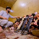 A butcher prepares sacrificial animal legs (Paye) during the second day of Eid al-Azha at Warsak road