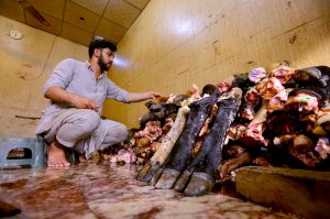 A butcher prepares sacrificial animal legs (Paye) during the second day of Eid al-Azha at Warsak road