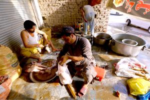 A butcher prepares sacrificial animal legs (Paye) during the second day of Eid al-Azha at Warsak road