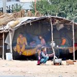 A young nomadic girl prepares a meal outside her makeshift shelter, reflecting the realities of daily life