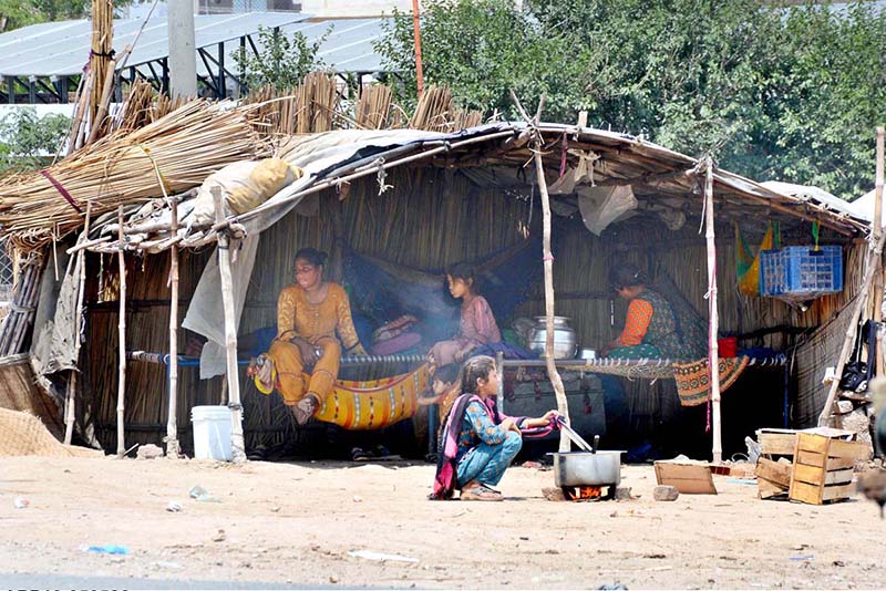 A young nomadic girl prepares a meal outside her makeshift shelter, reflecting the realities of daily life
