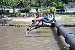 Children enjoy bathe in canal water to escape from the scorching heat wave in the city.