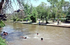 Children enjoy bathe in canal water to escape from the scorching heat wave in the city.