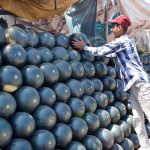 A vendor arranges watermelons in neat rows while selling them at his roadside stall to attract customers