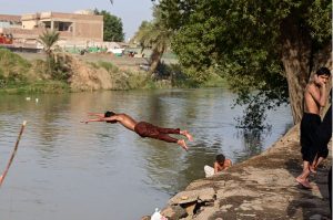 A youngster jumps into a canal for a refreshing bath on a scorching hot day.