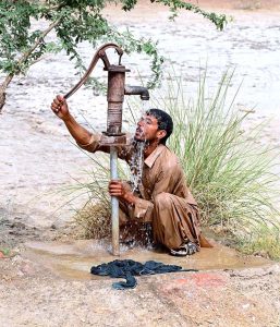 A person enjoying bathing under the hand pump to get relief from scorching hot weather.