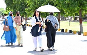 tudents are on their way under the cover of an umbrella to protect themselves from direct sunlight at the University of Sargodha during a hot day in the city.