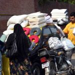 A family browses and purchases pillows and cushions from a vendor at the weekly bazaar in Anarkali