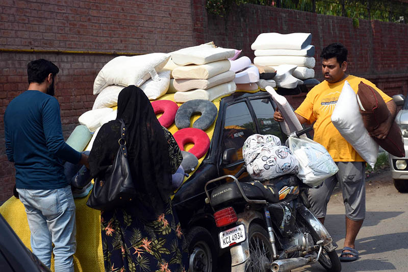 A family browses and purchases pillows and cushions from a vendor at the weekly bazaar in Anarkali