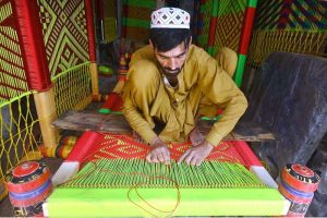 A worker is busy knitting a traditional bed (charpai) at his workplace in the Dabgari area.