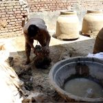 A laborer mixes natural clay and organic binders at a workshop to prepare raw material for traditional tandoor ovens